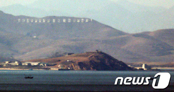 인천 옹진군 연평도 인근의 북한 해역에서 북한 어선이 조업하고 있다. 뒤로 보이는 산에 주체사상 문구가 세워져 있다. / 뉴스1 © News1 이명근 기자