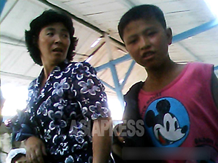 모자간으로 보이는 두 사람. 소년이 입은 셔츠에 미키마우스 그림이 보인다. 2013년 8월 북한 북부 국경도시의 모 시장. 사진-아시아프레스 제공