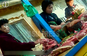 돼지고기를 다듬고 있는 장사꾼. 2012년 11월 북부 국경 도시의 시장. 북한 시장에서 판매되는 돼지고기는 대부분 껍질을 벗기지 않는다. 소비자가 요구하는 경우 껍질을 벗기지만, 대부분 그대로 구입한다. 사진-아시아프레스 제공