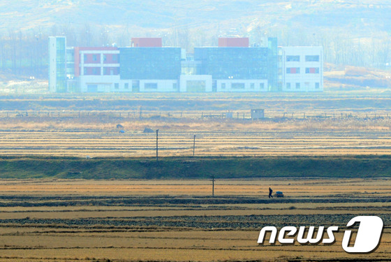 북한 기정동 마을 들녘을 지나는 주민 너머로 개성공단이 보이고 있다. 2014.11.12/뉴스1 © News1 한재호 기자
