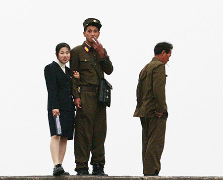 북한 군인 두 명과 그 중 한 명의 팔짱을 하고 있는 북한 여성의 모습/조선 DB