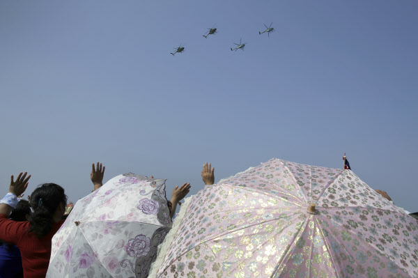 24일 북한 원산에서 양산을 쓴 여성 등이 북 공군의 휴즈 MD-500 헬기들의 에어쇼를 바라보며 손을 흔들고 있다./연합뉴스[출처] 본 기사는 조선닷컴에서 작성된 기사 입니다